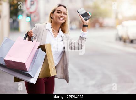 Je me promènais ici. Une jeune femme attirante qui fait descendre son taxi est en plein shopping dans la ville avec un téléphone portable à portée de main. Banque D'Images