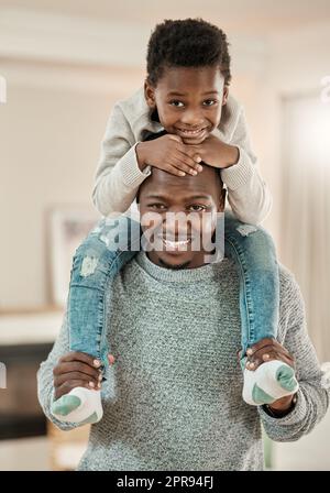 Je vais le soulever de la bonne façon. Portrait court d'un beau jeune homme portant son fils sur ses épaules dans le salon à la maison. Banque D'Images