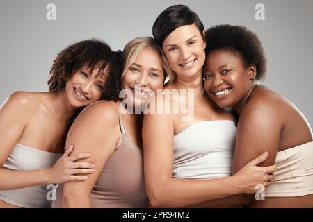 Les femmes qui se tiennent ensemble gagnent ensemble. Un groupe diversifié de femmes se tenant et s'embrassant dans le studio. Banque D'Images