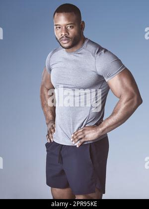 J'ai travaillé dur pour ce corps. Un beau jeune homme debout seul sur fond bleu dans le studio. Banque D'Images