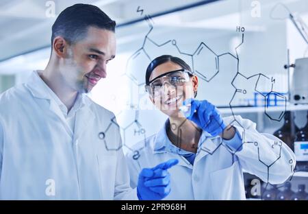 Shes reliant les points. Deux jeunes scientifiques travaillant sur une planche de verre dans leur laboratoire. Banque D'Images