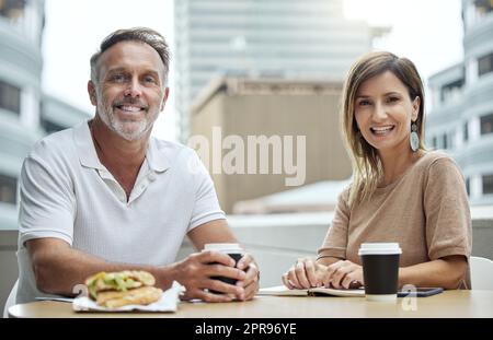 Seulement deux partenaires d'affaires qui profitent d'une réunion pendant le déjeuner. Portrait de deux hommes d'affaires qui déjeunent ensemble à l'extérieur d'un bureau. Banque D'Images