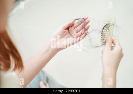 La femme asiatique a un problème avec la perte de cheveux longs attacher dans sa main. Banque D'Images