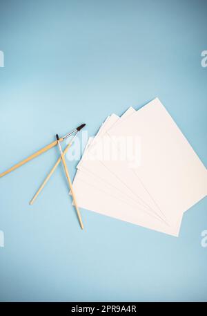 Des formes aquarelles de différentes tailles sont associées à du papier aquarelle sur fond bleu. Leçons de dessin. Banque D'Images