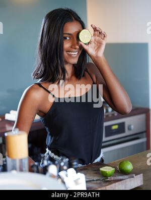 Il suffit d'ajouter une tranche de lime. Une belle jeune femme tenant une tranche de citron sur son œil. Banque D'Images