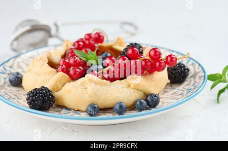 Tarte aux fruits avec des raisins rouges saupoudrés de sucre sur une table blanche Banque D'Images