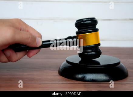 Main tenant avocat Gavel sur fond de table en bois. Banque D'Images