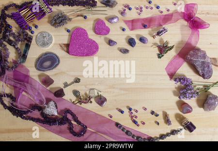 Bijoux violet et rose avec coeurs à paillettes et pierres améthystes sur fond en bois Banque D'Images