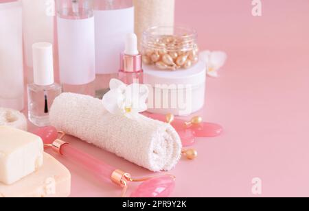 Pots cosmétiques naturels et accessoires de soin de la peau avec fleur d'orchidée blanche sur rose gros plan, espace de copie Banque D'Images