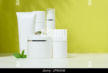 Tube de contenant en plastique blanc, un pot avec un couvercle pour les cosmétiques sur fond vert Banque D'Images