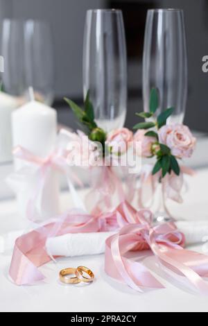 Anneaux et détails de mariage dans le style rose, qui sont sur la table. Banque D'Images