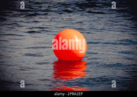 Bouée orange flottant sur l'eau de mer sombre et spectaculaire Banque D'Images