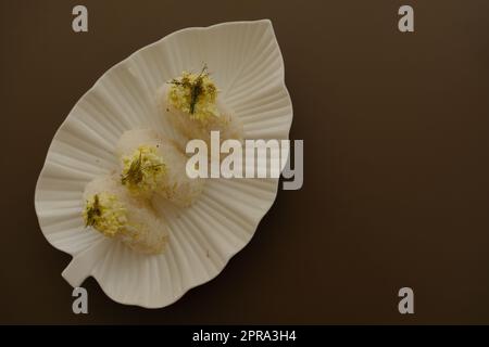 Assiette avec onigiri japonais traditionnel avec oeuf sur fond brun et belle plaque blanche avec forme de feuille Banque D'Images