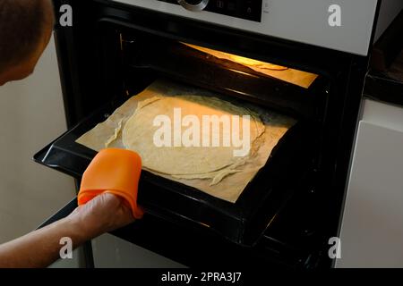 Gâteaux frais pour Napoleon gâteau pâte feuilletée pour le dessert Milfey. Pâtisseries françaises. Couches de gâteau Napoléon. L'homme a mis le gâteau seul. Banque D'Images