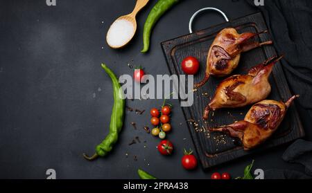 La friture des carcasses de cailles se trouve sur une planche de bois avec des légumes Banque D'Images