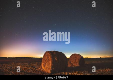 Comet Neowise C2020 F3 dans Starry Sky de nuit au-dessus de Haystacks dans le champ agricole d'été. Étoiles de nuit au-dessus du paysage rural avec balles de foin après la récolte. Concept agricole Banque D'Images