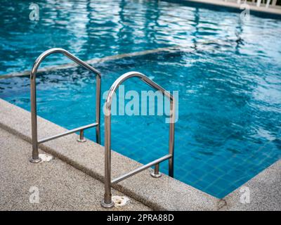 .Escalier en acier inoxydable vers la piscine. mains courantes de haut en bas de la piscine. Banque D'Images