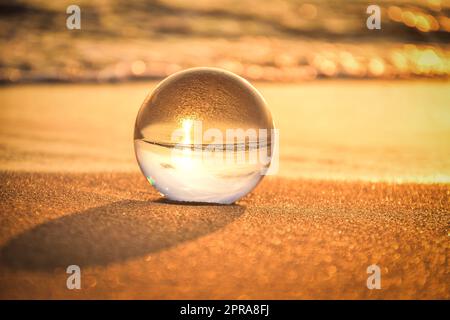 Idée abstraite avec de l'eau avec un effet intéressant. Boule de verre sur un fond flou sur une plage de bord de mer à Jastarnia, Pologne. Photo avec un peu profond Banque D'Images