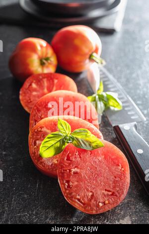 Tranches de tomates coeur de taureau sur table noire. Banque D'Images