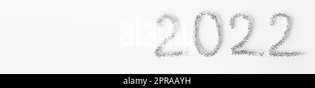 Baner Happy New Year 2022 écrit avec du papier d'aluminium et de la pluie du nouvel an sur un fond blanc isolé. Bonne année salutations. Banque D'Images