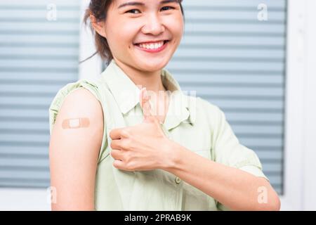 jeune femme montrant le pouce gestante vers le haut ou comme et son bras avec l'aide de bande de plâtre après le coronavirus Banque D'Images