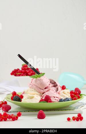 La glace à la vanille et à la framboise se ramasse sur une assiette ronde verte Banque D'Images