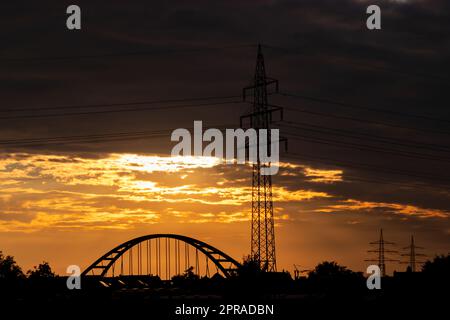 Le ciel doré aux rayons du soleil et à la lentille diffuse de l'énergie solaire avec une silhouette de pylône de tour d'électricité au coucher du soleil doré et un ciel orange pour une énergie durable ou des ressources renouvelables du crépuscule au soleil de l'aube Banque D'Images