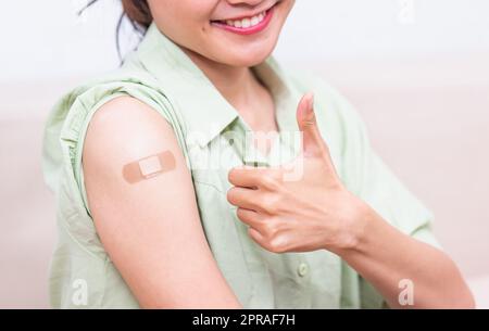 jeune femme montrant le pouce gestante vers le haut ou comme et son bras avec l'aide de bande de plâtre après le coronavirus Banque D'Images