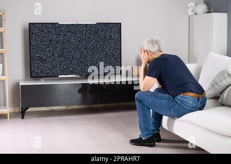 Triste femme avec la télécommande assis sur un canapé près de la télévision Banque D'Images