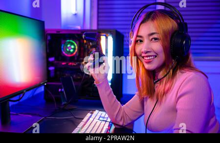 Un joueur souriant utilisant la manette de commande pour le tournoi joue à un jeu vidéo en ligne Banque D'Images