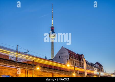 La célèbre Tour de Télévision de Berlin au crépuscule avec une motion blurred commuter train Banque D'Images