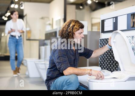 Client de sexe masculin regardant les toilettes à chasse d'eau en vente dans un magasin ou un centre commercial moderne Banque D'Images