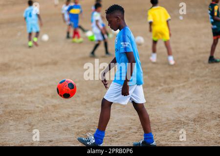 Un jeune joueur de football afro-colombien pratique le contrôle du ballon lors d'une session d'entraînement sur un terrain de jeu de terre à Necoclí, Antioquia, Colombie. Banque D'Images