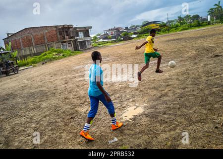 Les garçons afro-colombiens contrôlent le ballon lors d'une séance d'entraînement de football sur un terrain de jeu de terre à Quibdó, Chocó, Colombie. Banque D'Images