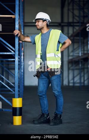 Le travail dur a des récompenses mais il a aussi ses risques. Un jeune homme qui éprouve des douleurs dorsales tout en travaillant dans un chantier de construction. Banque D'Images