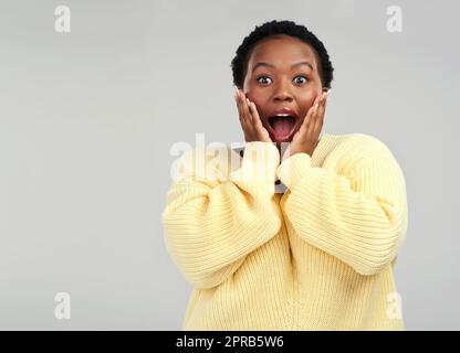 Je ne m'attendais pas à ça. Une jeune femme qui avait l'air surprise de poser sur un fond gris. Banque D'Images