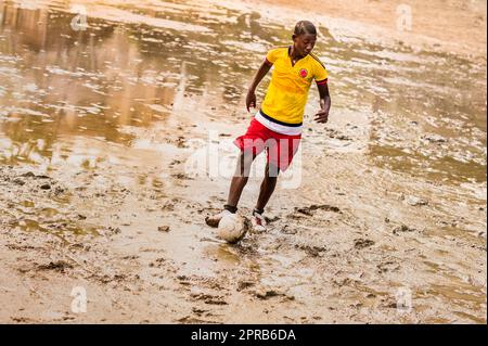 Un jeune joueur de football afro-colombien joue un match lors d'une session d'entraînement sur un terrain boueux à Quibdó, Chocó, Colombie. Banque D'Images