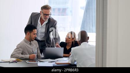 Ne laissez pas ce que vous ne pouvez pas faire trop de puissance. Un groupe de personnes en voyage d'affaires utilisant un ordinateur portable lors d'une réunion dans un bureau moderne. Banque D'Images