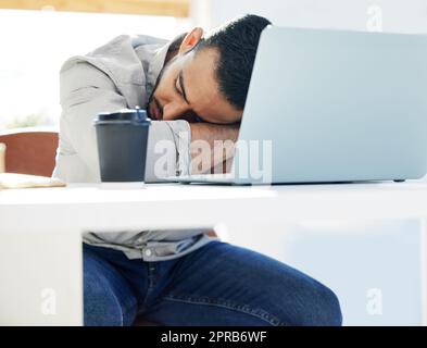 L'épuisement professionnel est réel, un jeune homme qui prend une sieste au travail dans un bureau moderne. Banque D'Images