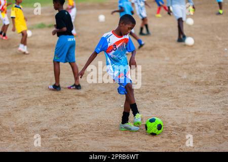 Un jeune joueur de football afro-colombien pratique le contrôle du ballon lors d'une session d'entraînement sur un terrain de jeu de terre à Necoclí, Antioquia, Colombie. Banque D'Images