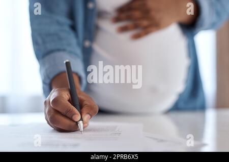 S'assurer que tout est en ordre avant d'entrer dans le travail. Une femme enceinte signant des documents. Banque D'Images