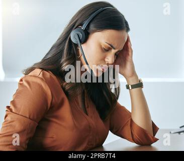 Pourquoi doivent-ils crier: Une jeune vendeuse attrayante assise seule dans son bureau et souffrant d'un mal de tête. Banque D'Images