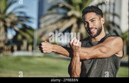 Commencez toujours par un étirement. Portrait d'un jeune homme sportif qui étire les bras tout en faisant de l'exercice à l'extérieur. Banque D'Images