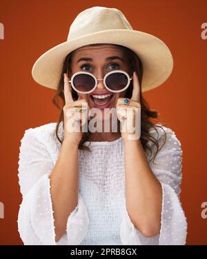 Dans une ambiance de petit jardin ensoleillée. Photo studio d'une jeune femme élégante posant sur un fond marron. Banque D'Images