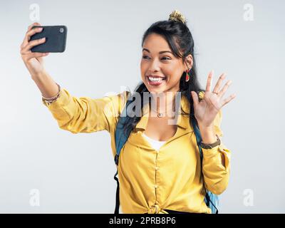 Recueillez des moments et non des choses. Photo studio d'une femme portant un sac à dos et prenant des selfies sur fond blanc. Banque D'Images