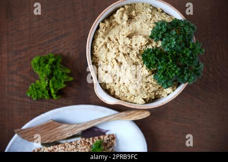 Bien manger est une forme de respect de soi. Grenaille d'un choux-fleur dans un plat de service en céramique accompagné de craquelins aux graines sur une table en bois. Banque D'Images