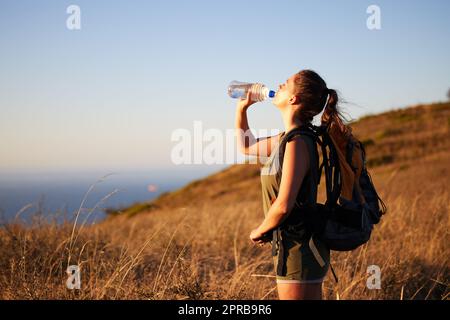 Partez à la découverte, mais assurez-vous d'avoir assez d'eau. Une jeune femme boit de l'eau pendant une randonnée. Banque D'Images