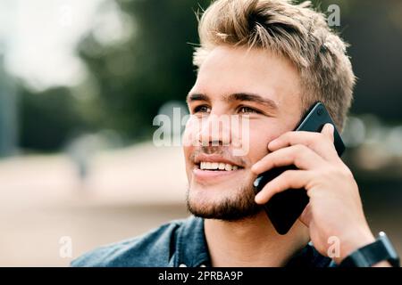 Quand le nouveau jour arrive, de nouvelles forces et de nouvelles pensées. Portrait rogné d'un jeune étudiant de sexe masculin en utilisant son téléphone portable à l'extérieur du campus. Banque D'Images