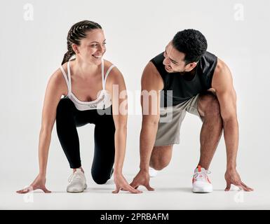 Votre course, votre rythme. Photo en studio d'un jeune homme et d'une femme sportif en position de départ sur fond blanc. Banque D'Images