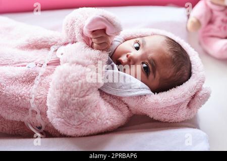 Je pense que mon nom est mignon, tout le monde m'appelle cela. Une adorable petite fille sur un poste de changement de couches à la maison. Banque D'Images